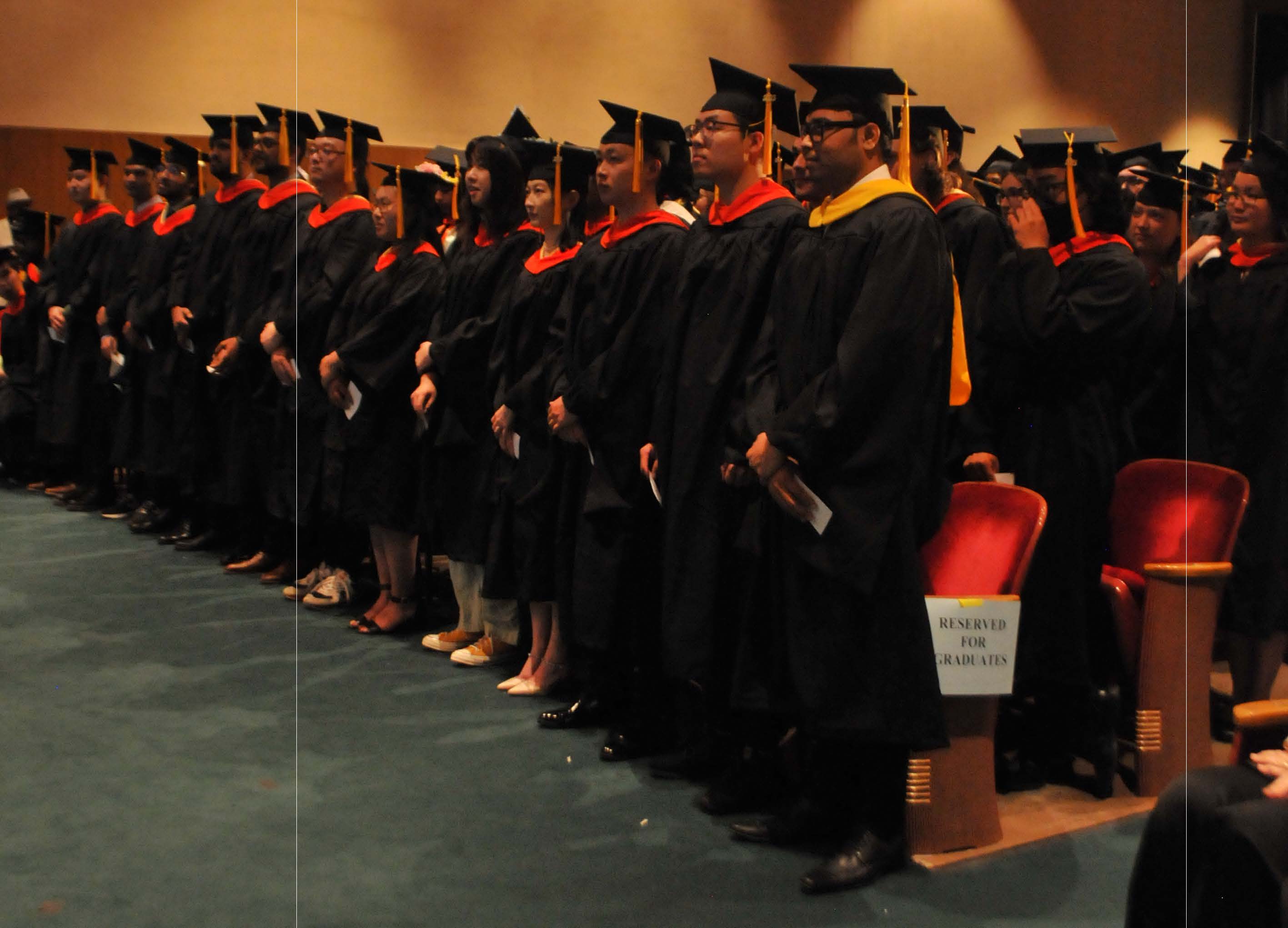 graduates stand at ceremony
