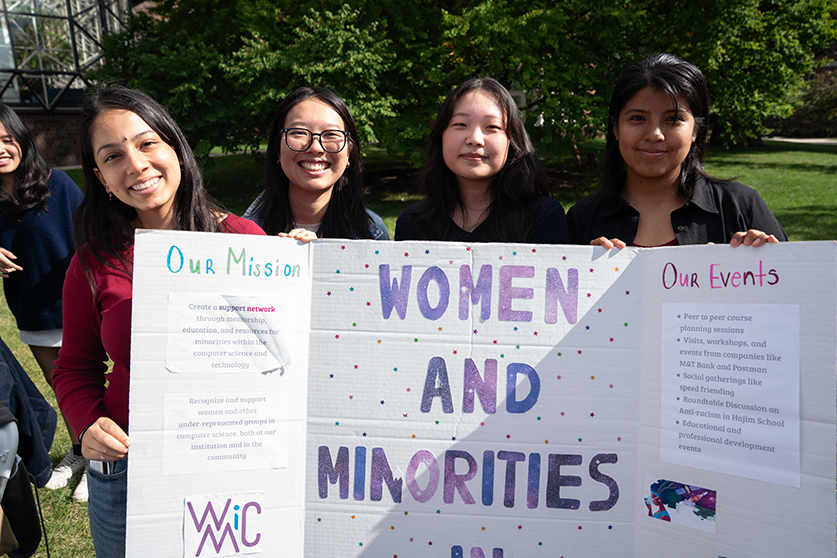 A group of students holding a club sign at a fair event.