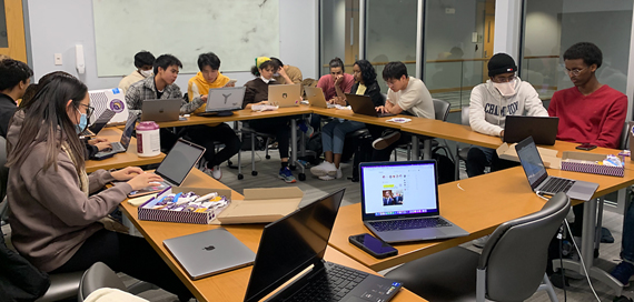 students with laptops sitting around tables in a circle