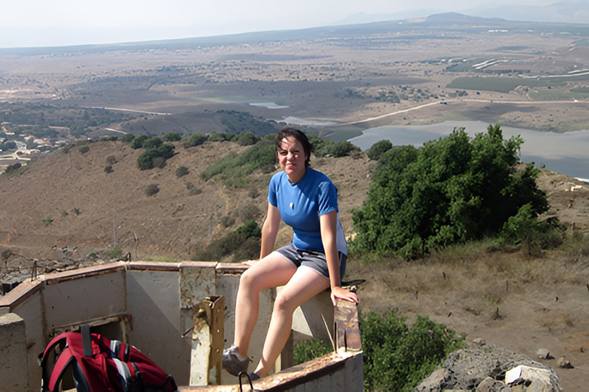 A student sitting on a ledge with an expansive vista behind them.