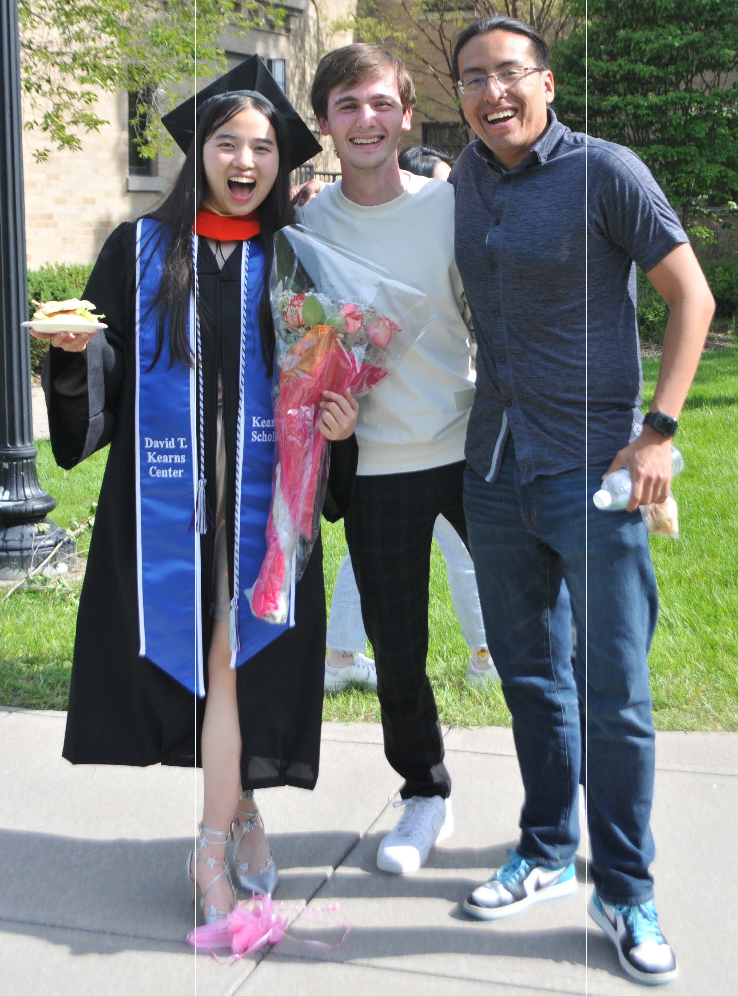 three students posing with graduate